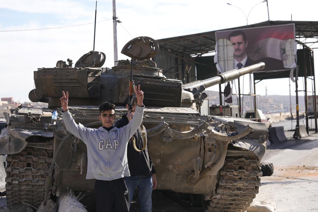 反政府武裝分子佔據大馬士革後,在政府軍坦克前展示勝利手勢。(美聯社)