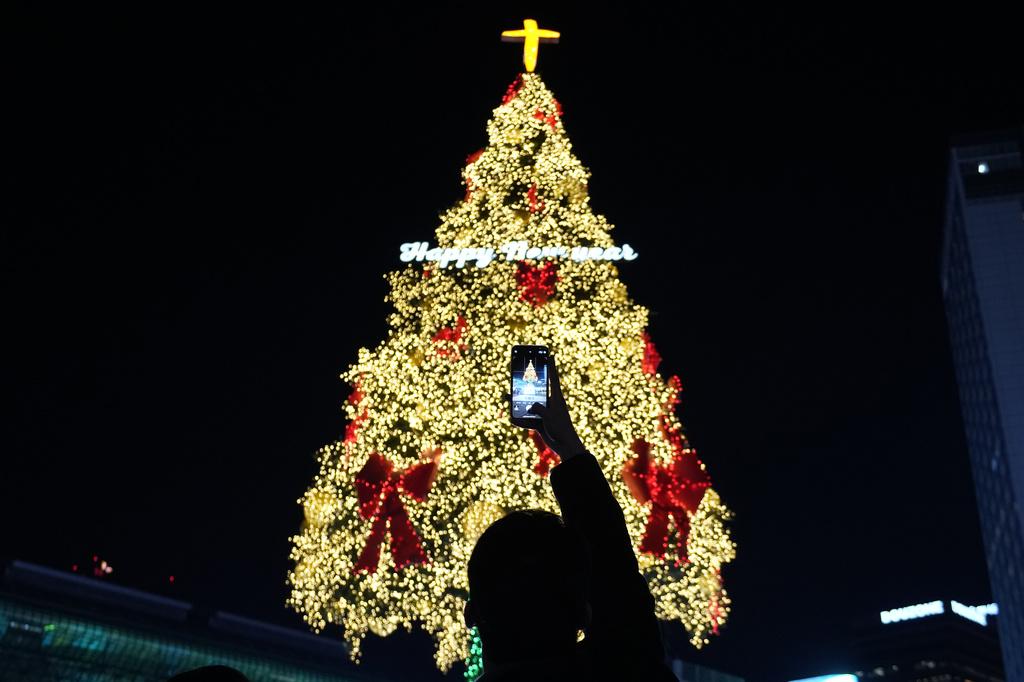圖為南韓首爾民眾在平安夜拍攝聖誕樹裝飾。(美聯社)