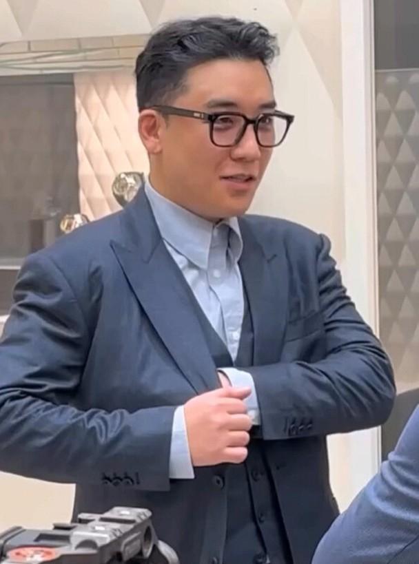 勝利日前身在外地,戴著黑框眼鏡及穿上藍色西裝疑似傾生意。