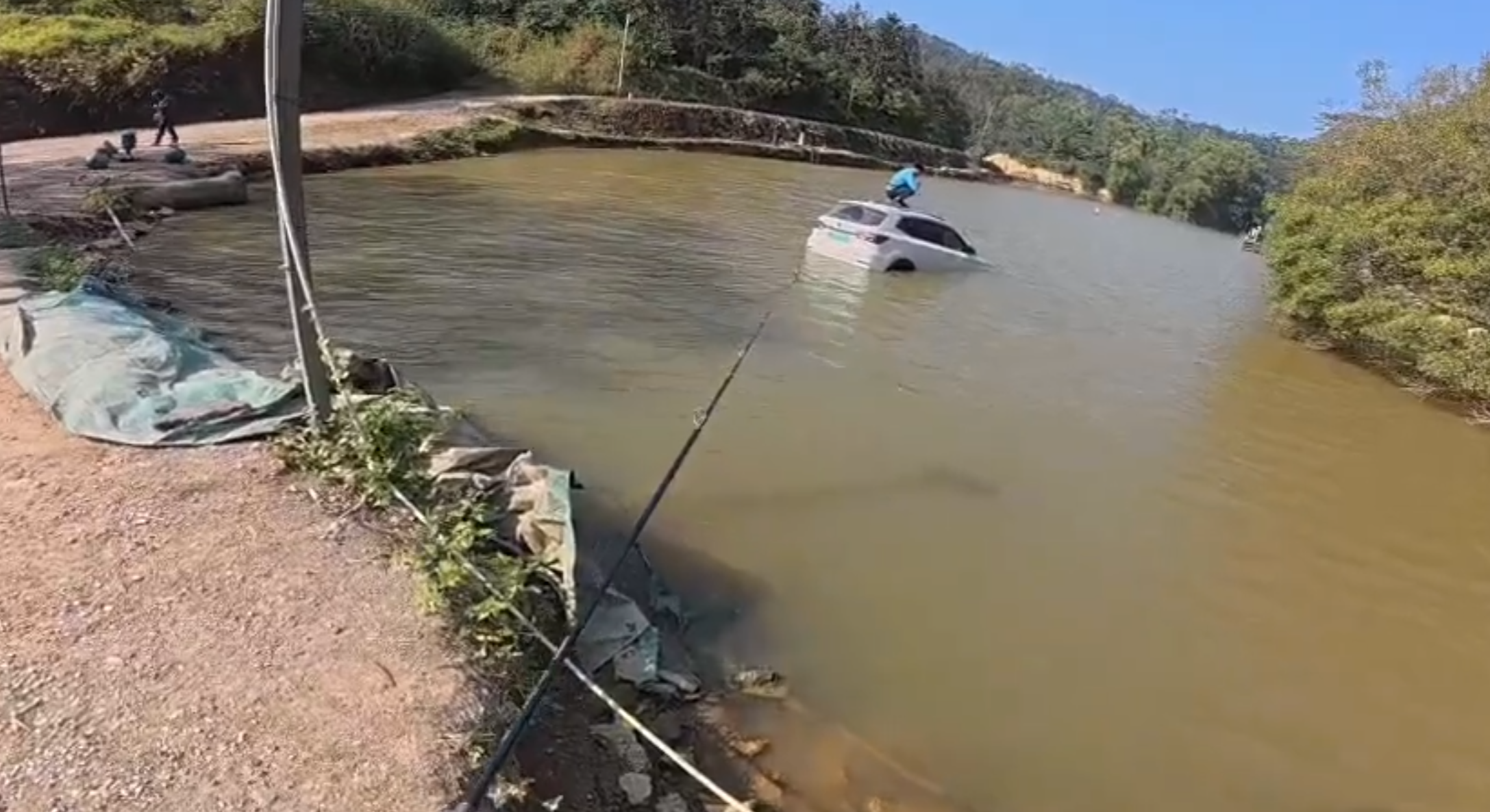 深圳有釣魚人士遇到一輛車墮湖,車主站在車頂處境危險。於是他伸出魚桿向車頂抛出魚絲,借助風力和水的浮力,將車輛「釣回」拉到岸邊。(影片截圖)