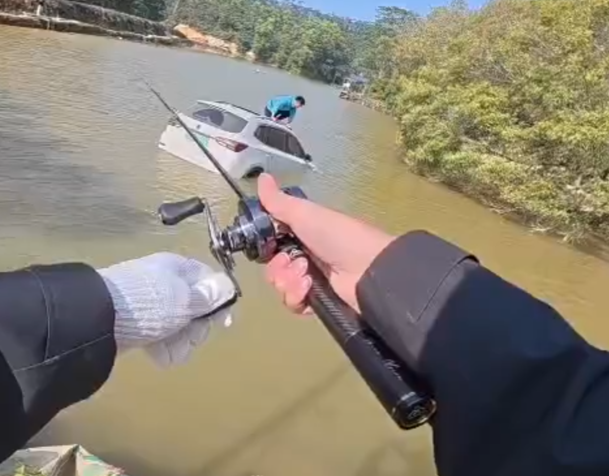 深圳有釣魚人士遇到一輛車墮湖,車主站在車頂處境危險。於是他伸出魚桿向車頂抛出魚絲,借助風力和水的浮力,將車輛「釣回」拉到岸邊。(影片截圖)