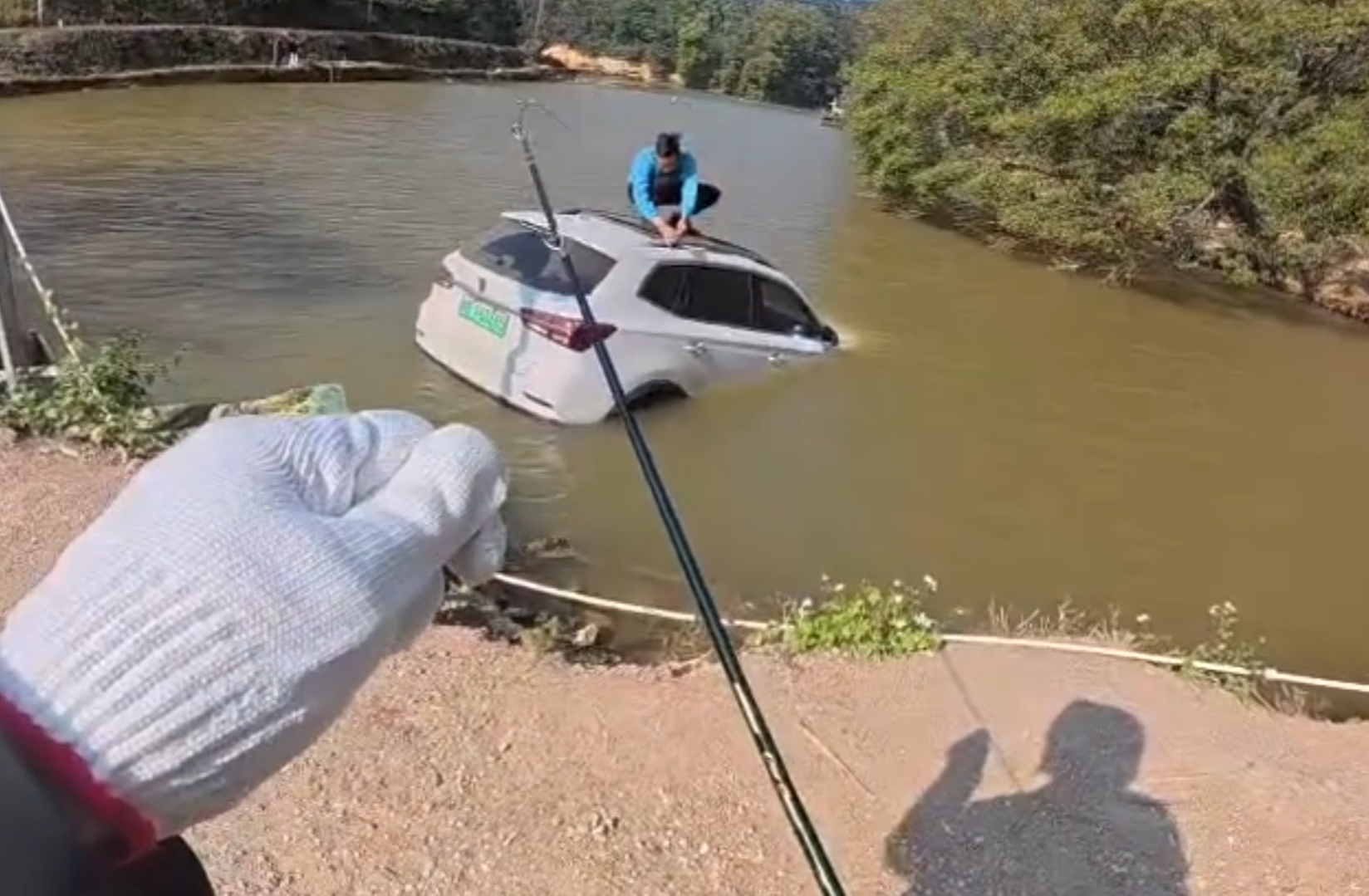 深圳有釣魚人士遇到一輛車墮湖,車主站在車頂處境危險。於是他伸出魚桿向車頂抛出魚絲,借助風力和水的浮力,將車輛「釣回」拉到岸邊。(影片截圖)