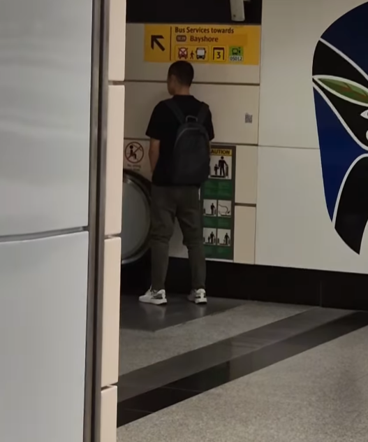 一名中國籍男子在新加坡歐南園地鐵站內,向一條扶手電梯小便。(影片截圖)
