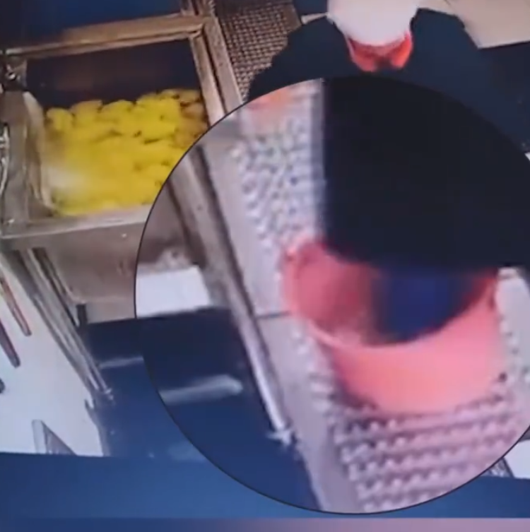 江西新余市第十六中學食堂有一名戴廚師帽的員工用腳多次踩踏水桶內的食材,當時他還穿著水靴。(影片截圖)