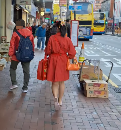 北角有大媽穿大紅色連身裙,以「人肉利是封」打扮不斷向途人詢問「有無利是啊?」(影片截圖)