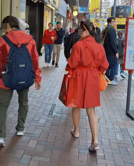 北角有大媽穿大紅色連身裙,以「人肉利是封」打扮不斷向途人詢問「有無利是啊?」(影片截圖)