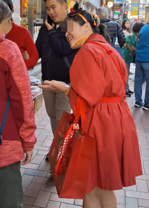 北角有大媽穿大紅色連身裙,以「人肉利是封」打扮不斷向途人詢問「有無利是啊?」(影片截圖)