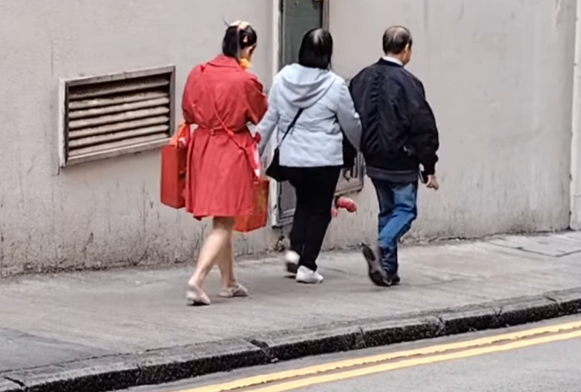 北角有大媽穿大紅色連身裙,以「人肉利是封」打扮不斷向途人詢問「有無利是啊?」(影片截圖)