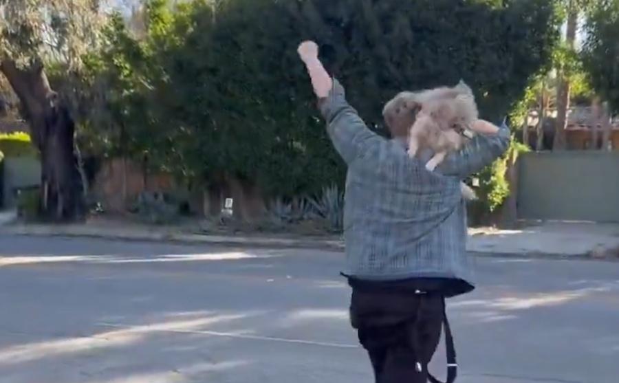 他緊抱著愛犬情緒激動,並開心地歡呼走著,他感謝上天的恩賜。(X)