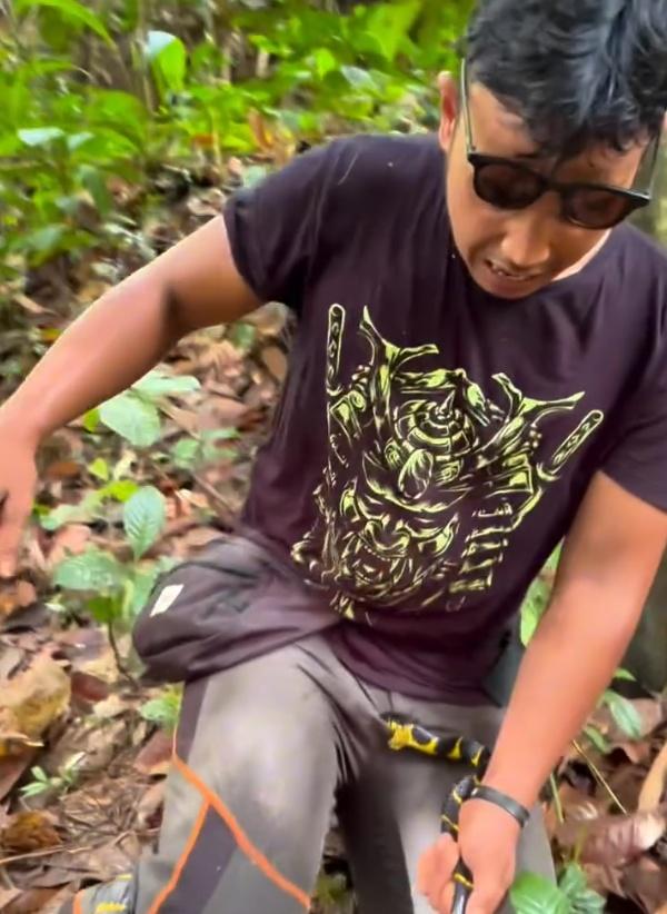 由於蛇沒有要鬆口的意思,使得他滿頭大汗,臉上露出痛苦表情,只能痛苦坐在地上。(IG)