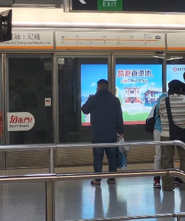 網民拍攝到一名中年漢在港鐵香港站月台上等車時食煙。(網片截圖)