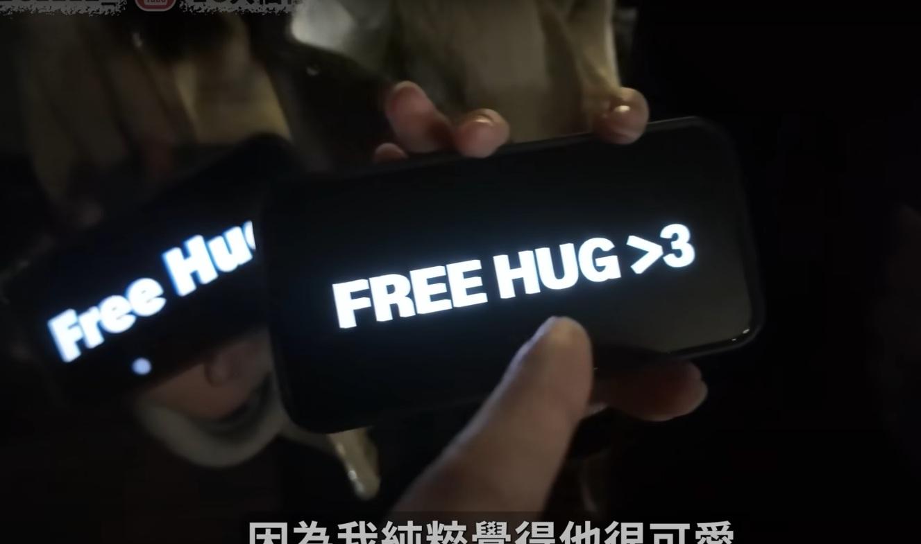 現場有少女手持手機,顯示「Free Kiss」和「Free Hug」的標語。(網片截圖)
