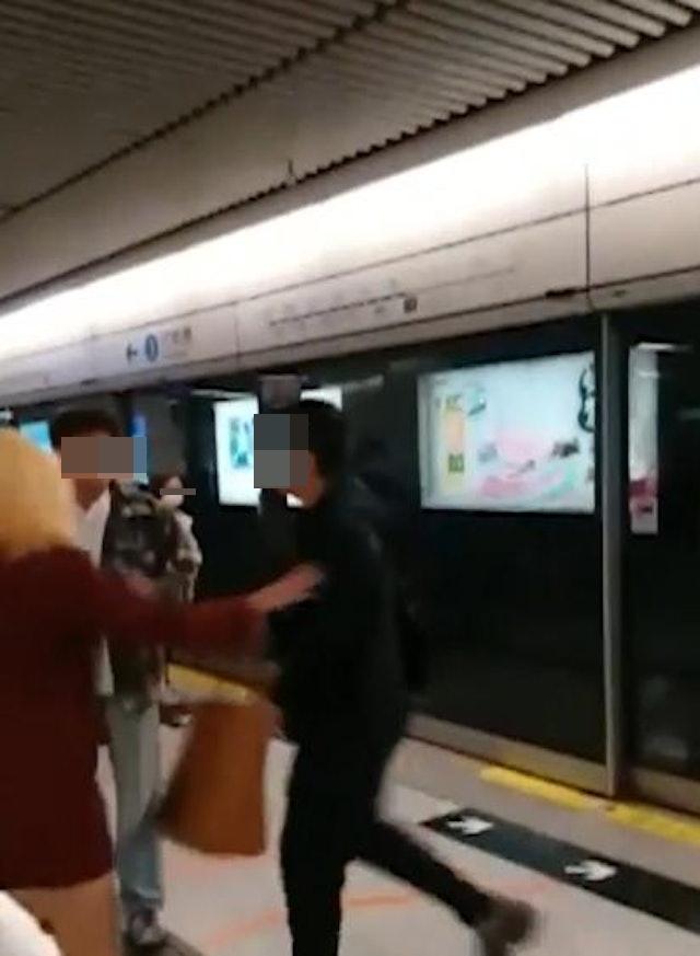 穿著格仔上衣的男子正與黑衣男爭執,而一名身穿紅衣的金髮女則試圖上前勸解。(網片截圖)