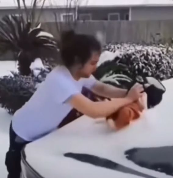 美國德州一名男子,以3個月嬰兒的身體除去車上的積雪。(網上截圖)