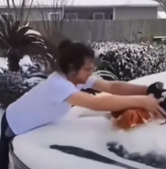 美國德州一名男子,以3個月嬰兒的身體除去車上的積雪。(網上截圖)