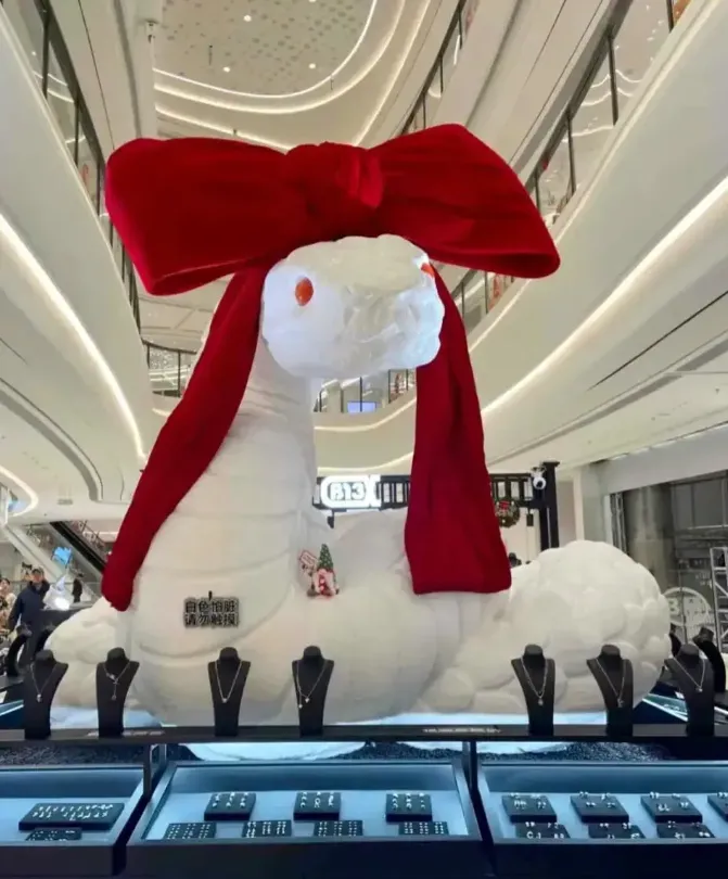 山東青島一個商場的白蛇裝置被戴上紅色蝴蝶結。(小紅書)