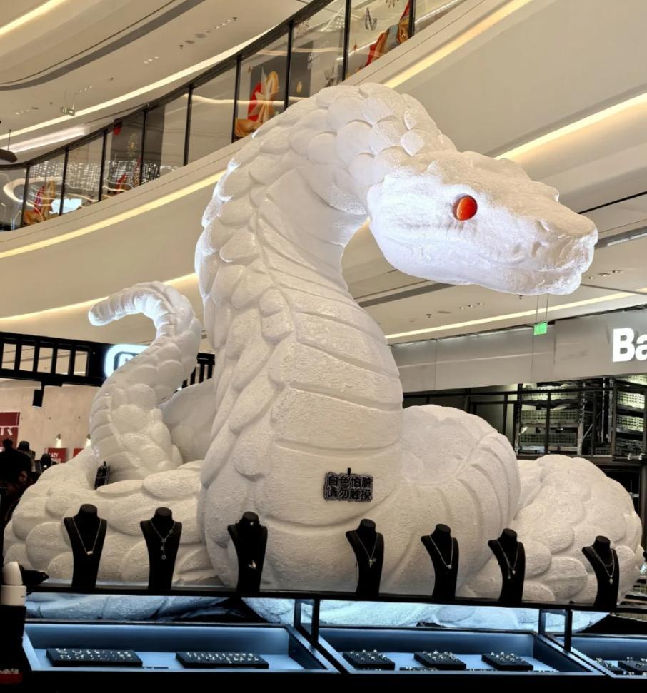 山東青島一個商場的白蛇裝置被戴上紅色蝴蝶結前。(小紅書)