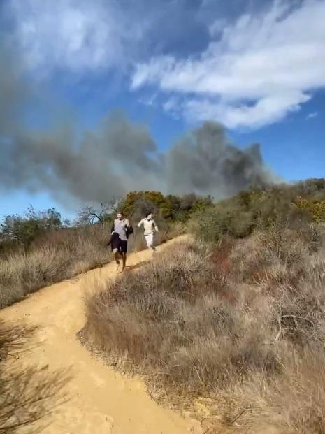 山火在後方,青年拔足狂奔。(互聯網)