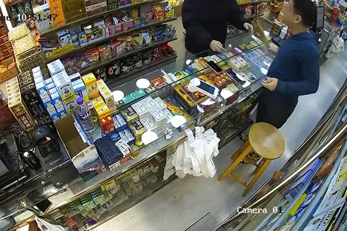 店員獲悉該張為偽鈔後折返,取起沙嗲魚串作勢打向男子。(網上影片截圖)