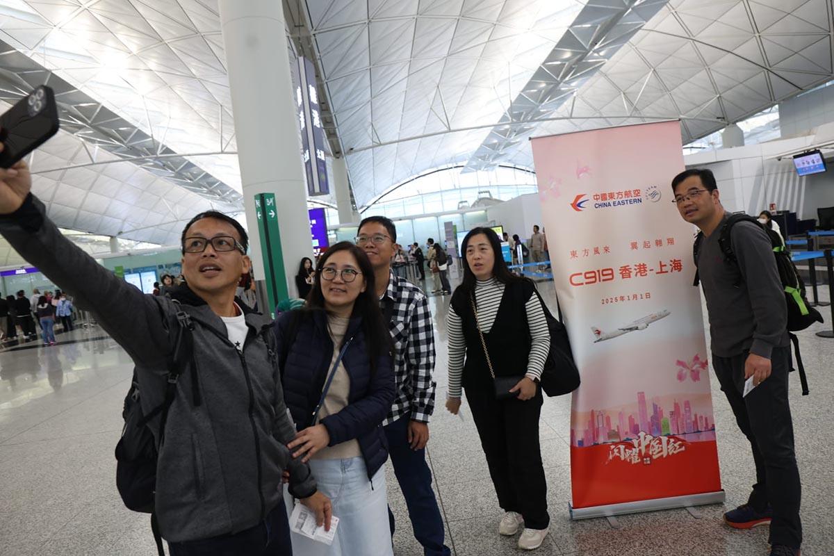 有乘搭國產C919客機首航的乘客在辦理登機手續櫃位前合照。