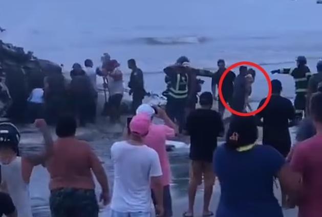 民眾從飛機殘骸救出小孩(紅圈示)。(互聯網)