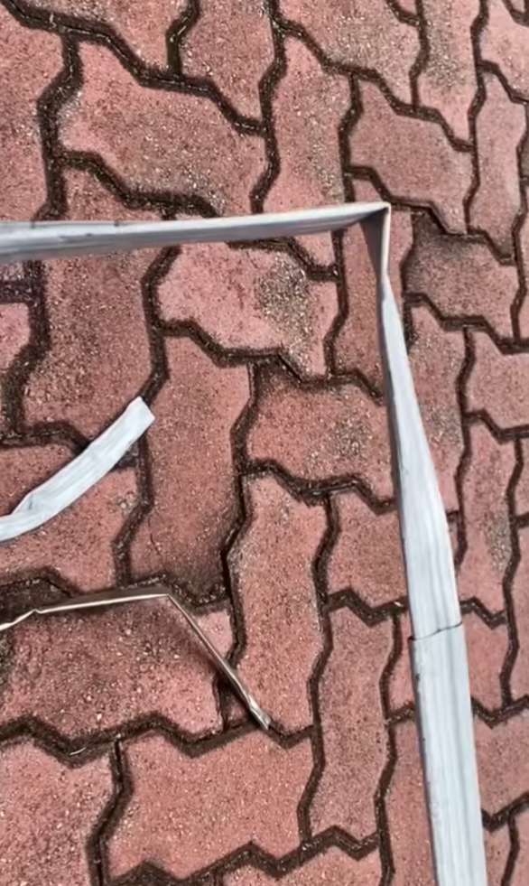 司機下車後展示3支扭曲變形的條狀物,近鏡所見為鋁條,私家車車頭冚及擋風玻璃有刮花損毀㾗迹。(facebook香港突發事故報料區影片截圖)