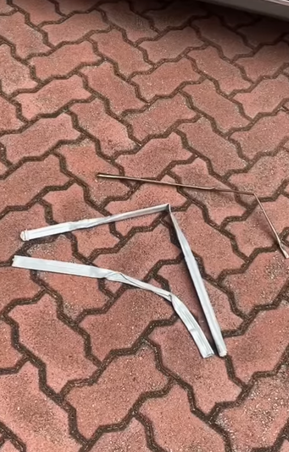 司機下車後展示3支扭曲變形的條狀物,近鏡所見為鋁條,私家車車頭冚及擋風玻璃有刮花損毀㾗迹。(facebook香港突發事故報料區影片截圖)