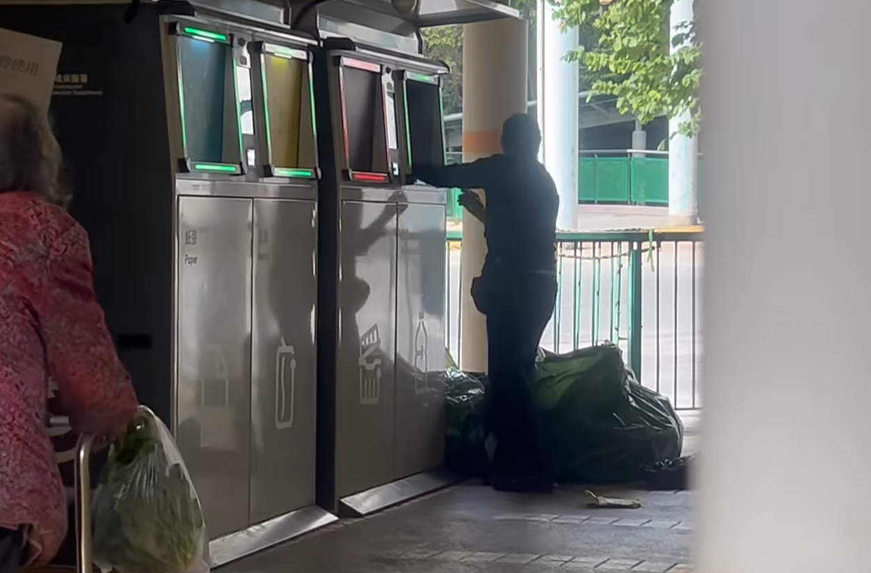 女子打開智慧回收桶的玻璃樽回收口,並持續從一個大形回收袋內攞出有膠袋或膠兜承載的樽,直接放入回收口。(@fb慈雲山資訊交流/Mana Li影片截圖)