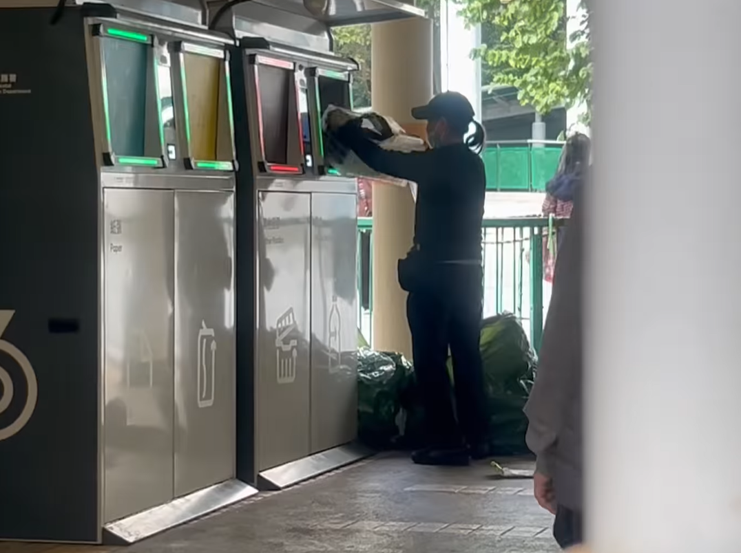 女子打開智慧回收桶的玻璃樽回收口,並持續從一個大形回收袋內攞出有膠袋或膠兜承載的樽,直接放入回收口。(@fb慈雲山資訊交流/Mana Li影片截圖)