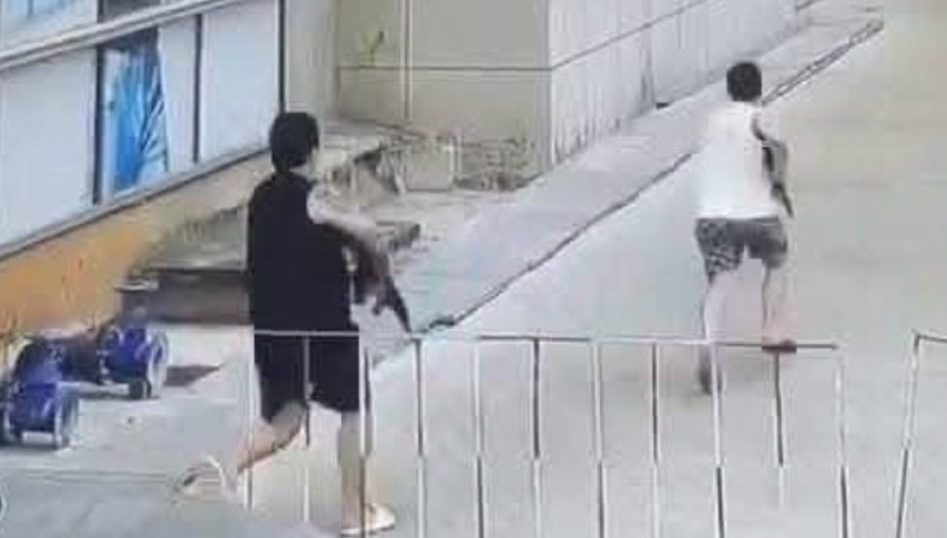 影片顯示,有兩名男子拿著兩支步槍跳下車衝進樓內,另有一名男子手持一把短槍對準一輛汽車的後座。(影片截圖)