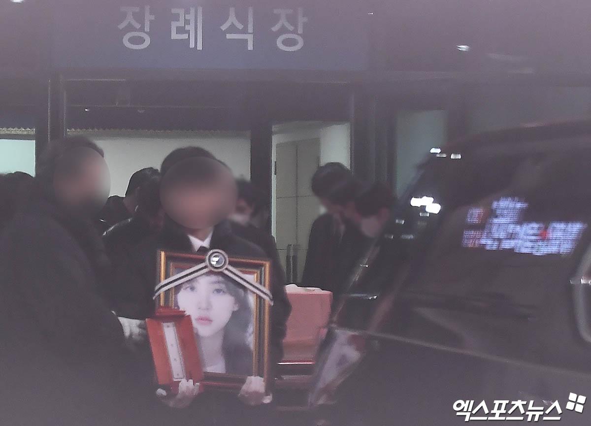 男親屬拿著金賽綸的靈牌與遺照步出靈堂。