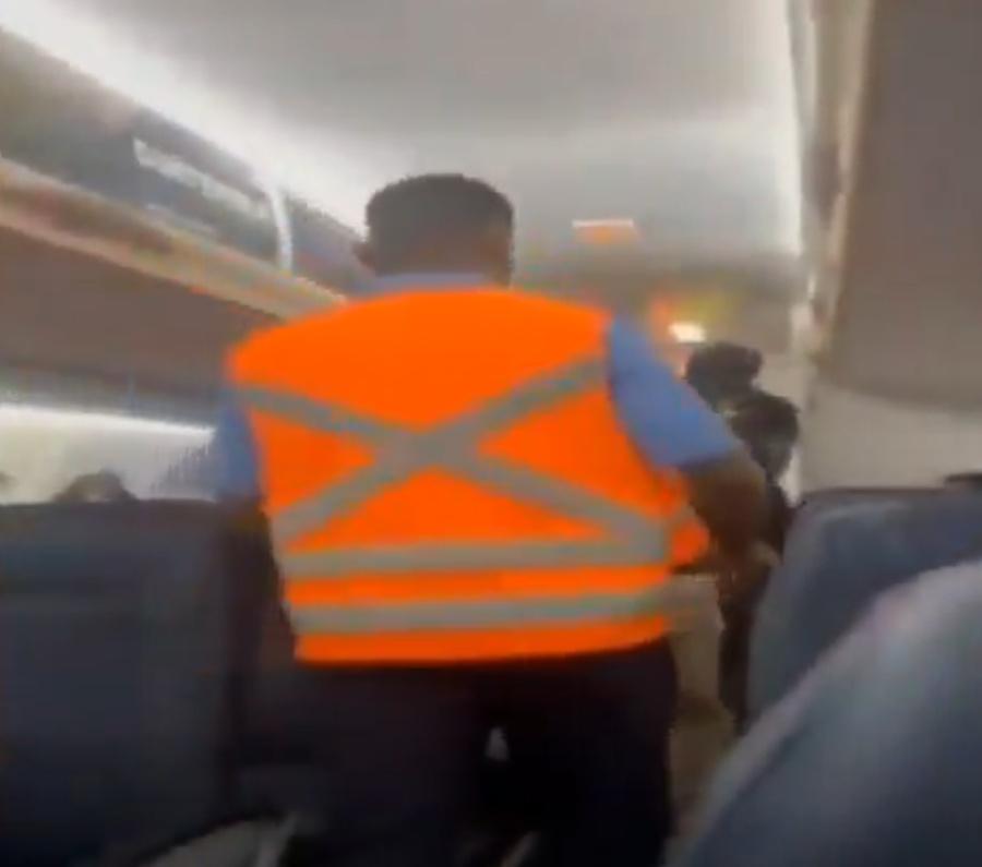 一名身著黑衣的男子在多名國家警察押解下離開機艙。(X)