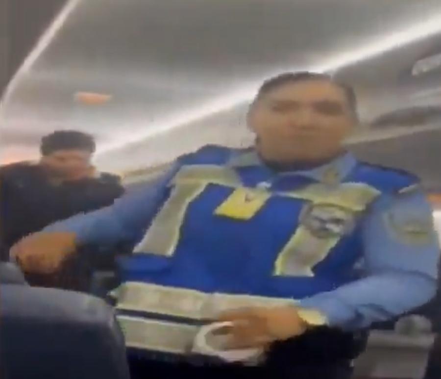 一名身著黑衣的男子在多名國家警察押解下離開機艙。(X)