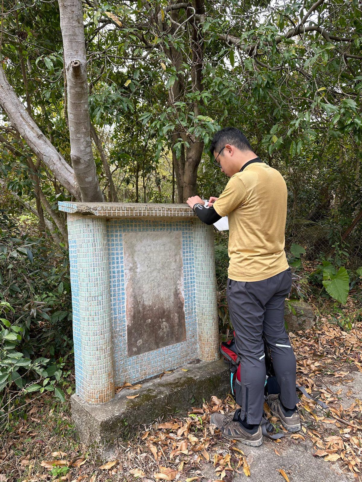 謝淏嵐暫時記錄了數十塊石碑資料,圖為謝正抄錄荃灣蓮花山的一塊石碑(受訪者提供)