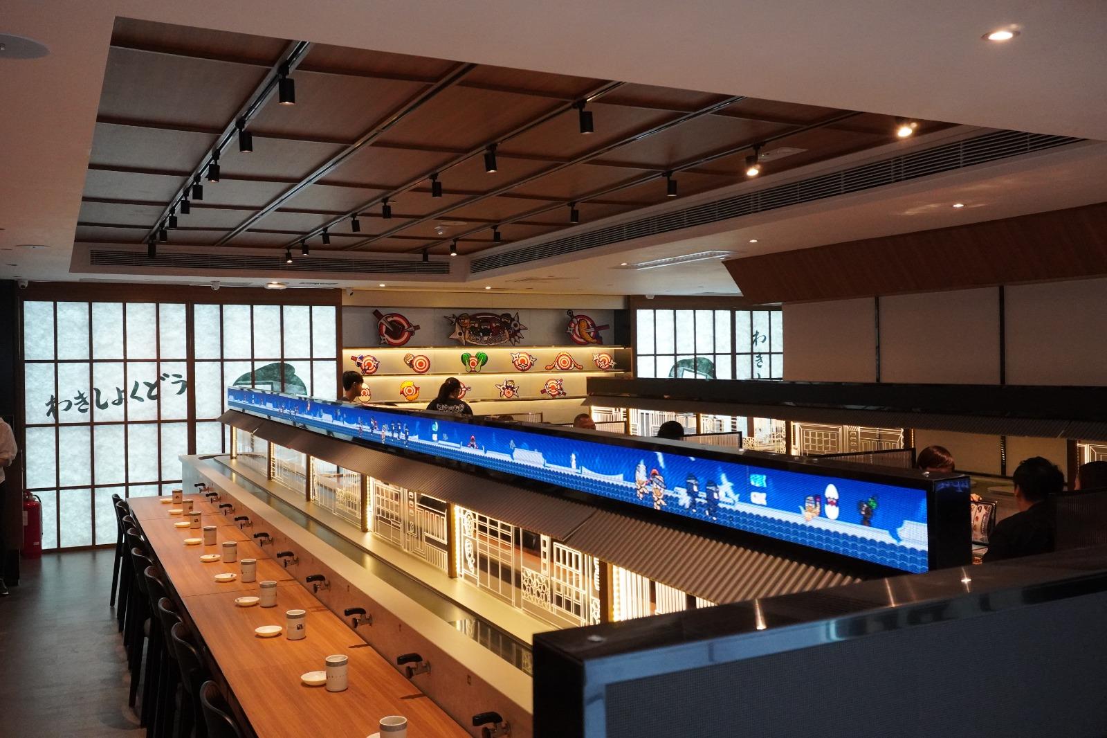 。餐軌上使用日本古式屋簷設計襯托,上方裝置了LED屏幕,播放結合品牌設計的忍者IP動畫,氣氛玩味。