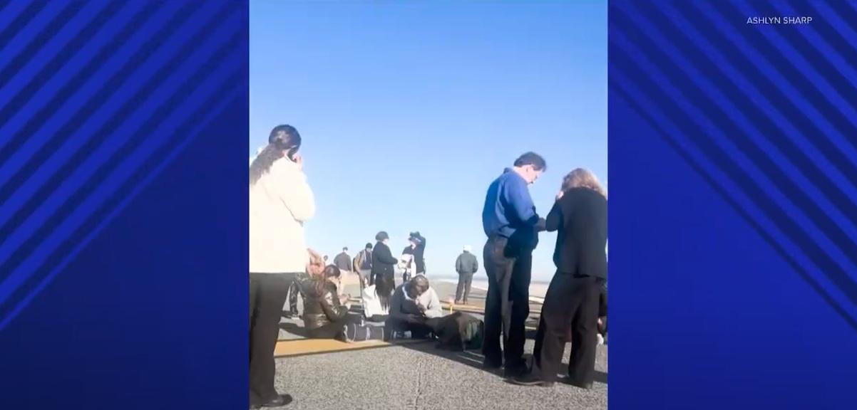 乘客疏散到跑道,有人坐著等候。(互聯網)