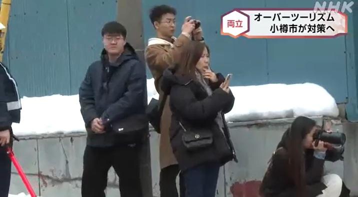 北海道小樽市有遊客在街上拍攝,保安員(圖左)在旁維持秩序。(互聯網)