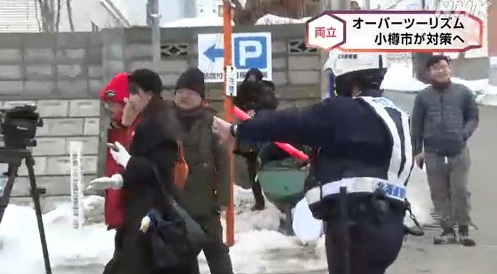 北海道小樽市有遊客在街上拍攝,保安員維持秩序,指示遊客不要走出馬路。(互聯網)