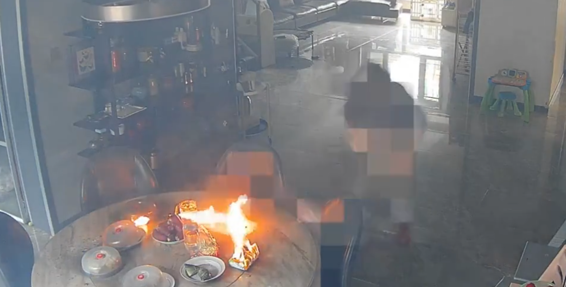 事發在河北唐山一戶人家,閉路鏡頭可見於上周六(15日)早上10時許,已準備餸菜的電動餐枱突然爆炸起火,火光四射,「連桌帶餸」一齊燃燒。事發時屋內兩名女子慌亂中不會用滅火器,最終以防火布撲滅火焰。(影片截圖)