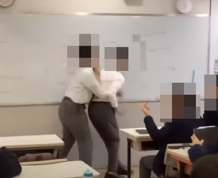 另一影片根據課室、冬季校服和窗外環境,可能也是聖保羅書院,影片中兩名身高差不多的學生,於下午1時40分在課室白板前打架,一名身材相對壯健的學生起身後揮拳反擊,其他同學上前做「和事佬」介入。(影片截圖)
