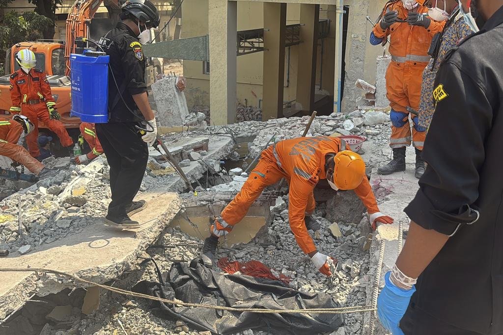 緬甸地震, 圖為緬甸與印度救援隊周一在曼德勒U hla thein佛寺搜救,發現一具遺體,用黑布覆蓋。(美聯社)