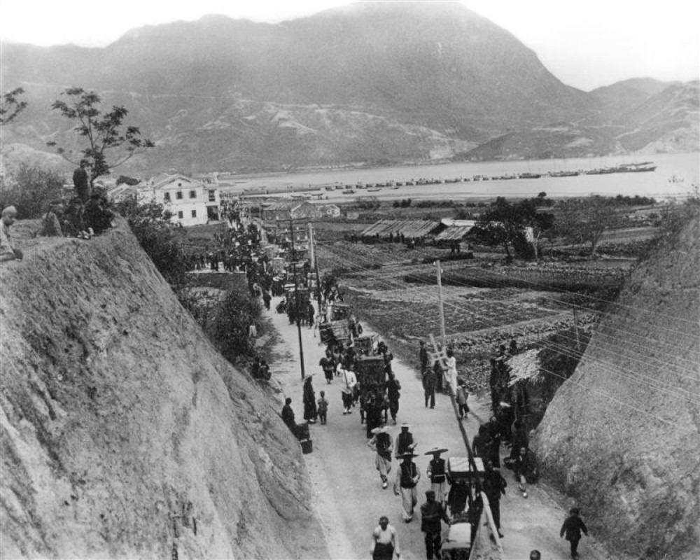 圖片攝於1900年代的九龍寨城外,照片中的隊列估計是附近村落的打醮活動。圖右可見向海伸延的龍津石橋。(圖片來源:《「龍津橋及其鄰近區域」歷史研究》/香港歷史博物館)