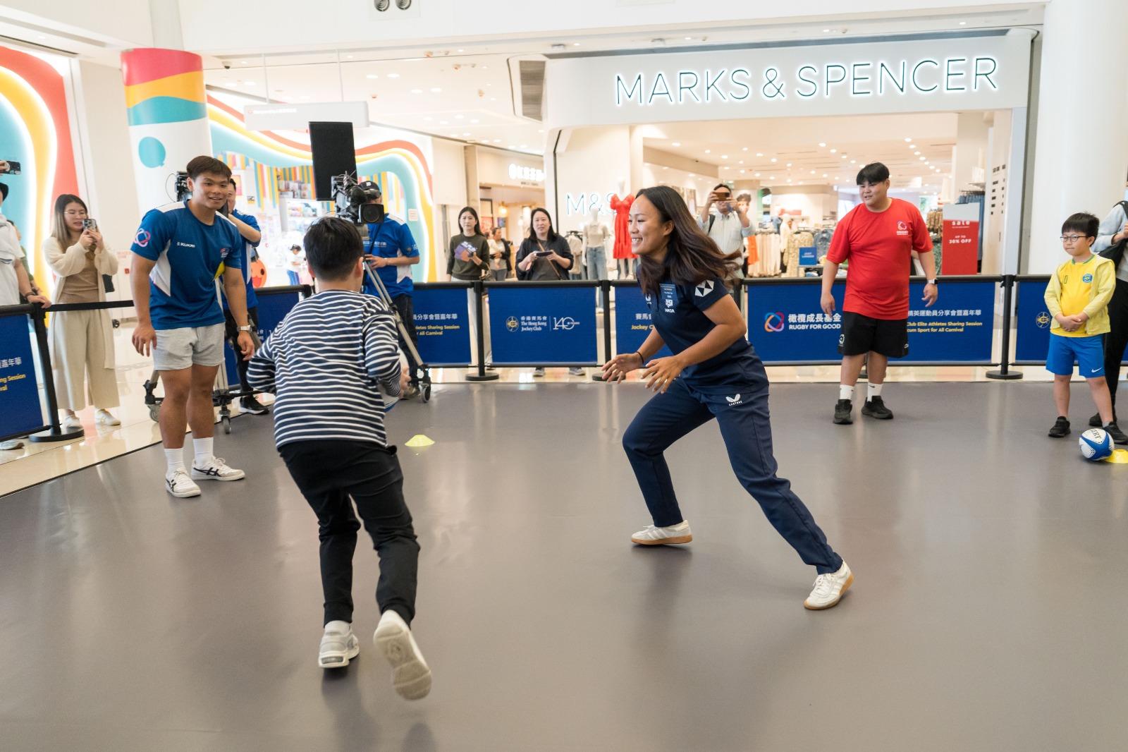 賽馬會社區七人欖球計劃2025展開,香港七人欖球女子隊的潘慧欣與市民試玩欖球。