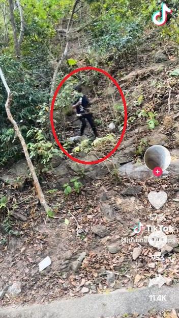 泰國人爬上山邊取回手機。(互聯網)