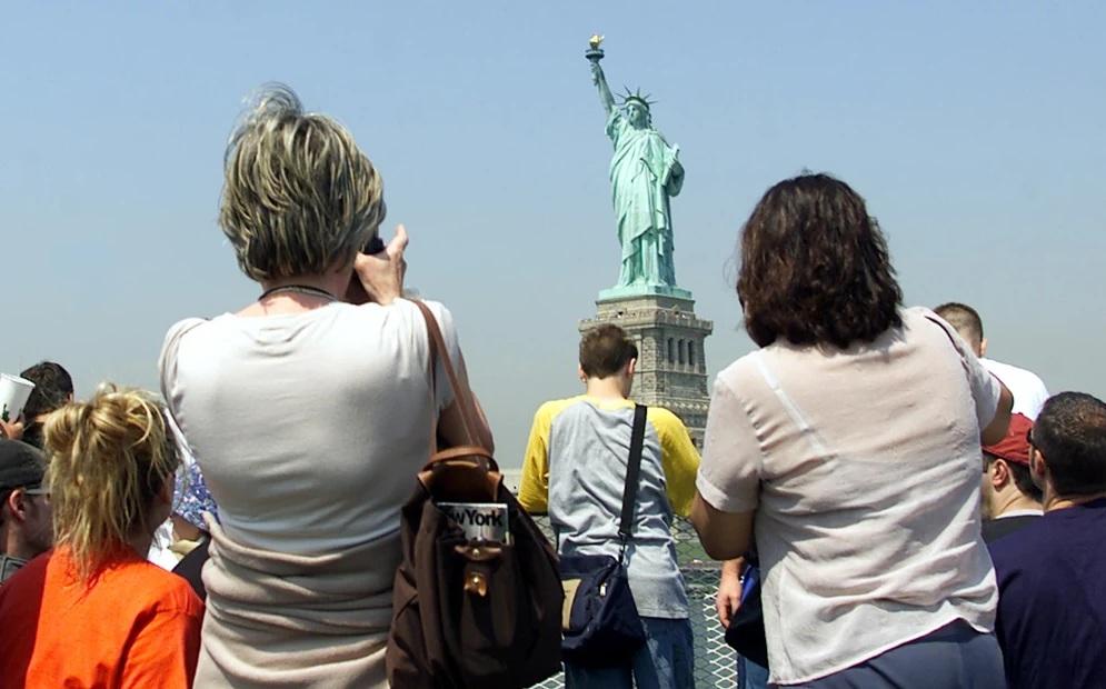 遊客在紐約景點自由神像前打卡。(資料圖片)