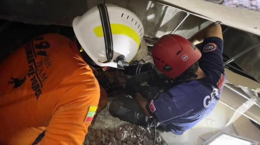 緬甸地震|緬甸消防部門和土耳其救援隊在內比都一棟倒塌酒店的廢墟中開始救援。被困男子26歲,是酒店工作人員。(緬甸消防部門圖片)