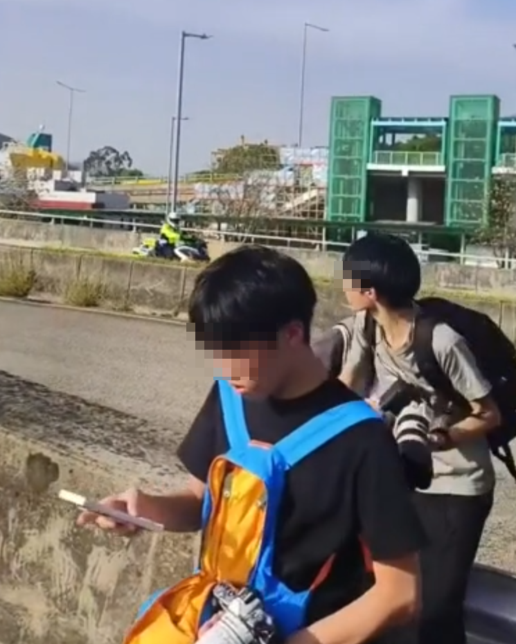 約20名少年巴士迷在大欖青山公路一帶企出公路影相,其間被兩名鐵騎交通警員驅趕。(影片截圖)