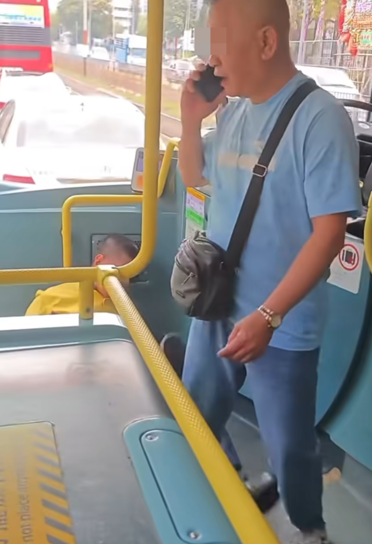 有港鐵巴士車長躺在車頭位置,指罵一名穿淺藍色上衣的阿叔推跌他,令他受傷。(fb群組「車cam L(香港群組)影片截圖)