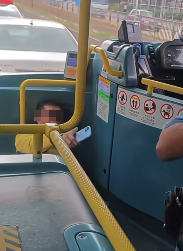 有港鐵巴士車長躺在車頭位置,指罵一名穿淺藍色上衣的阿叔推跌他,令他受傷。(fb群組「車cam L(香港群組)影片截圖)