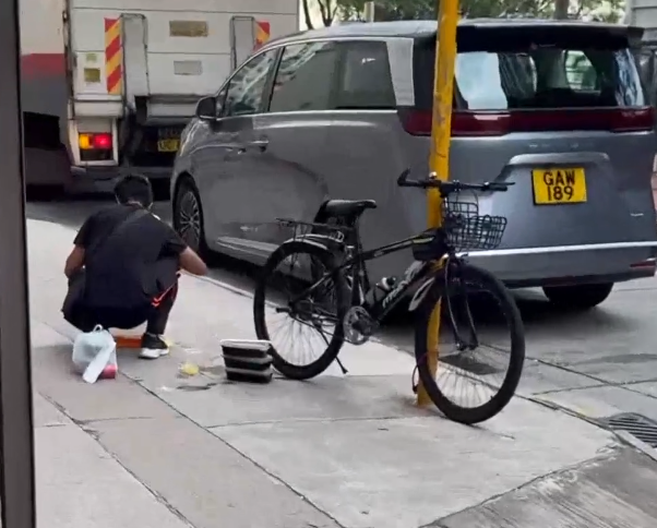 一名外賣員倒瀉了兩杯凍檸茶在外賣袋內,遂在路邊蹲地「急救」,將袋內茶水倒回杯內,試圖變回原狀。(Threads)